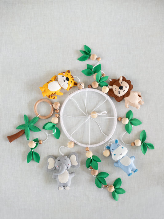 Baby Being handcrafted felt cot mobile featuring a lion, tiger, elephant, hippo, palm tree, wooden teether ring, and leafy details for a safari-inspired nursery.