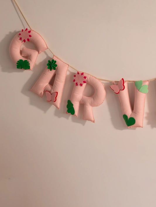 Close-up of the Garvita personalized felt name banner showcasing handcrafted floral embellishments, butterflies and soft pastel lettering.