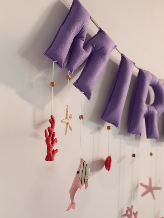 Close-up of the ‘MIR’ section of the personalized Miraya felt name banner featuring handcrafted purple letters and ocean-themed hanging décor.