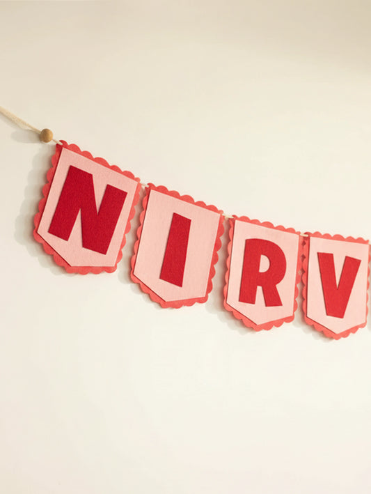 Close-up of the ‘NIRV’ letters on the personalized Nirvair felt name banner with handcrafted red felt lettering.