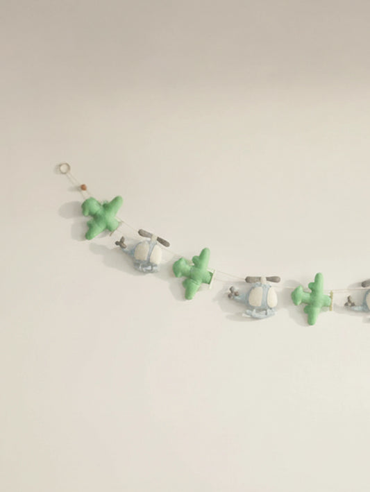 Close-up of the left section of the To The Moon felt banner showcasing handcrafted airplanes and helicopters in soft pastel tones.