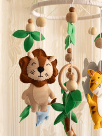 Handcrafted felt lion from the Baby Being baby cot mobile with wooden beads and leafy accents, adding a playful safari touch to modern nursery décor.