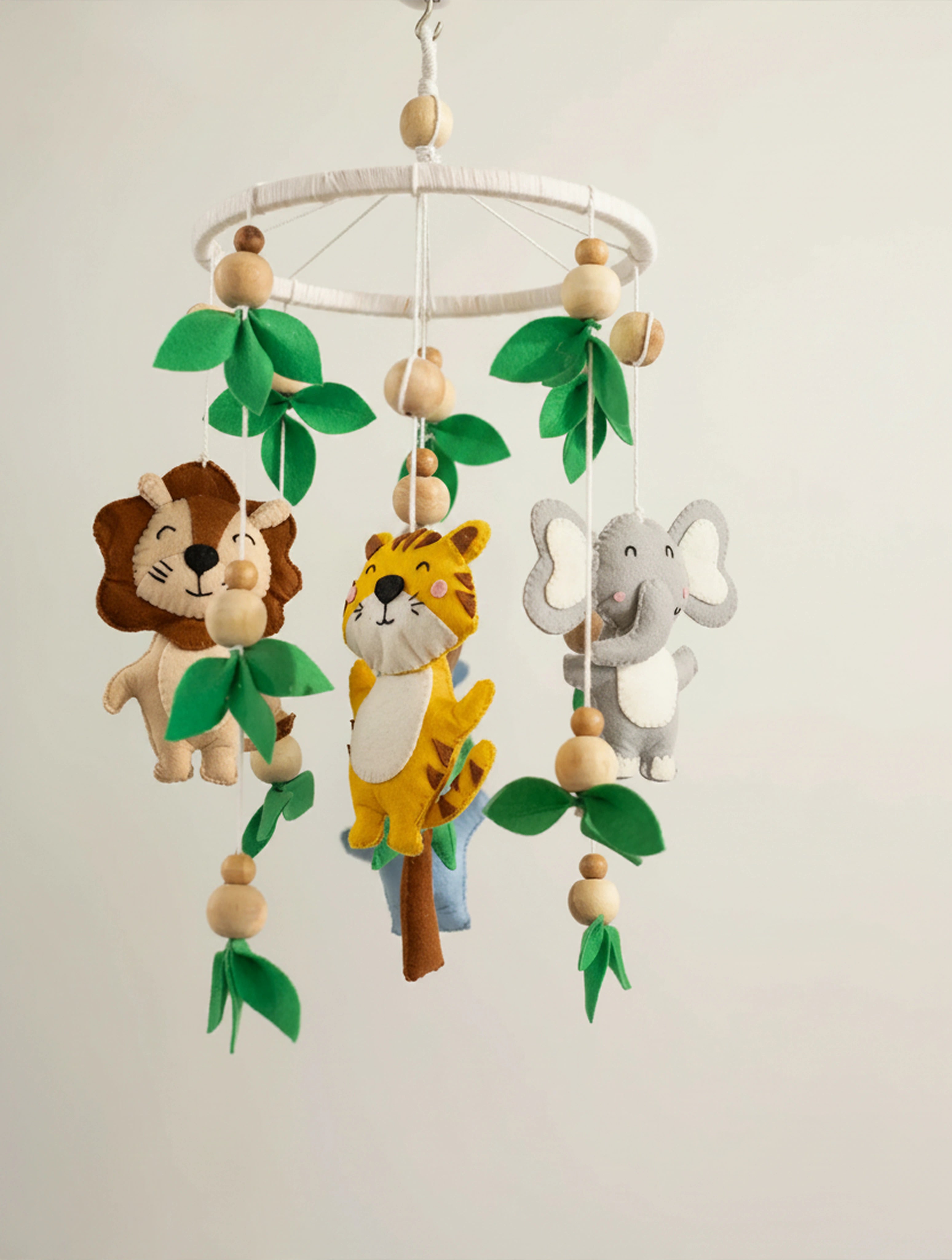 Baby Being premium handcrafted felt baby cot mobile with safari animals, wooden beads, and leafy accents, designed to create a soothing jungle-themed nursery.