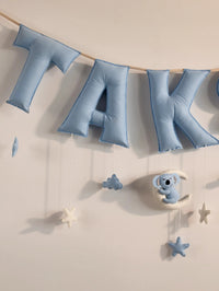 Close-up of the ‘TAK’ letters on the personalized Taksh felt name banner with handcrafted blue nursery décor and hanging sea-themed ornaments.