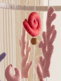 Soft felt coral branches paired with a handcrafted spiral shell ornament from the Deep in the Ocean nursery mobile for calming ocean-themed baby rooms.