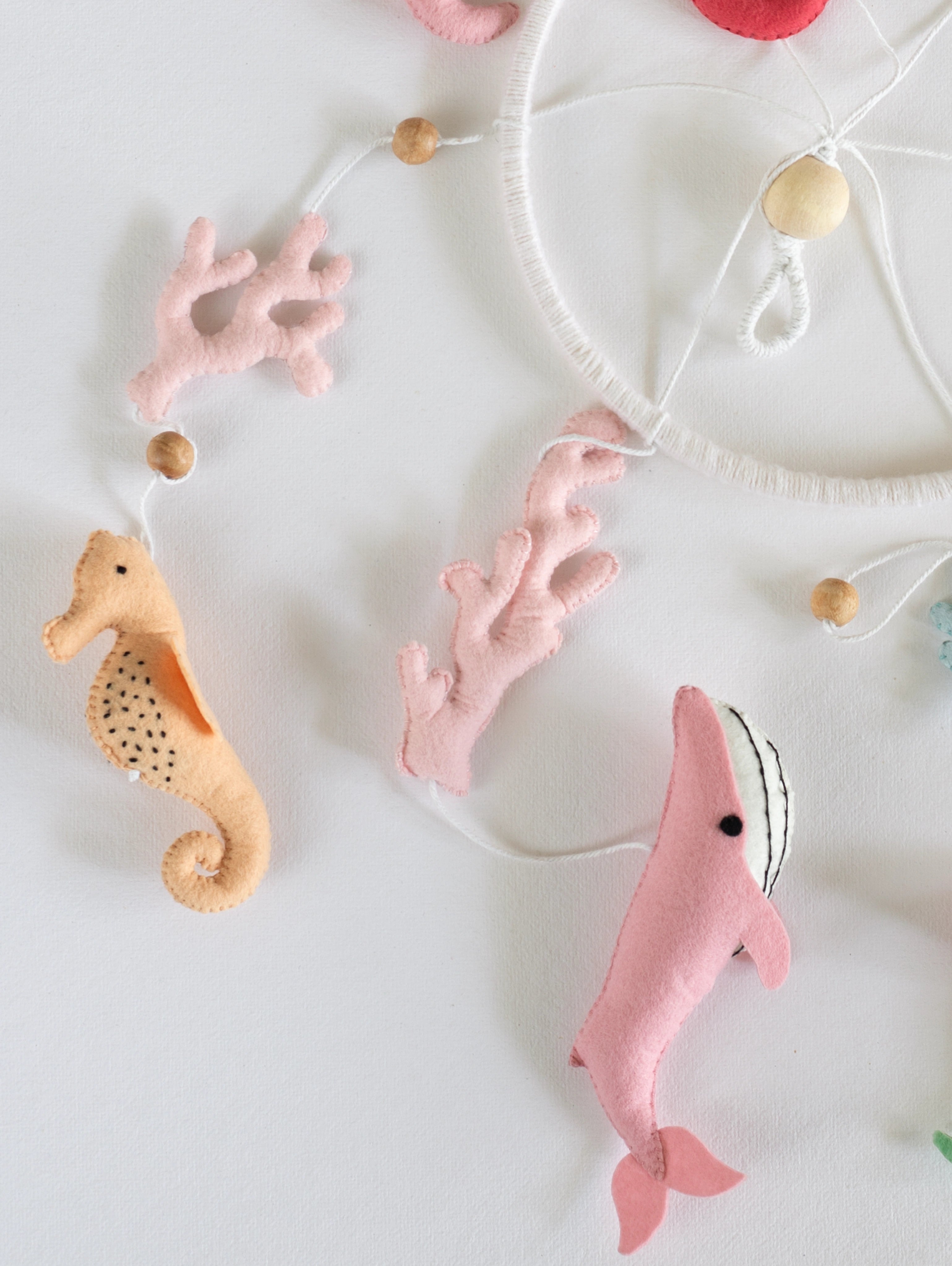 Pastel felt seahorse and whale hanging ornaments from the Deep in the Ocean crib mobile, handcrafted for soothing coastal-themed baby nurseries.