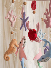 Deep in the Ocean handcrafted felt baby mobile featuring sea creatures, coral, shells, and starfish, beautifully suspended above a crib for peaceful nursery styling.