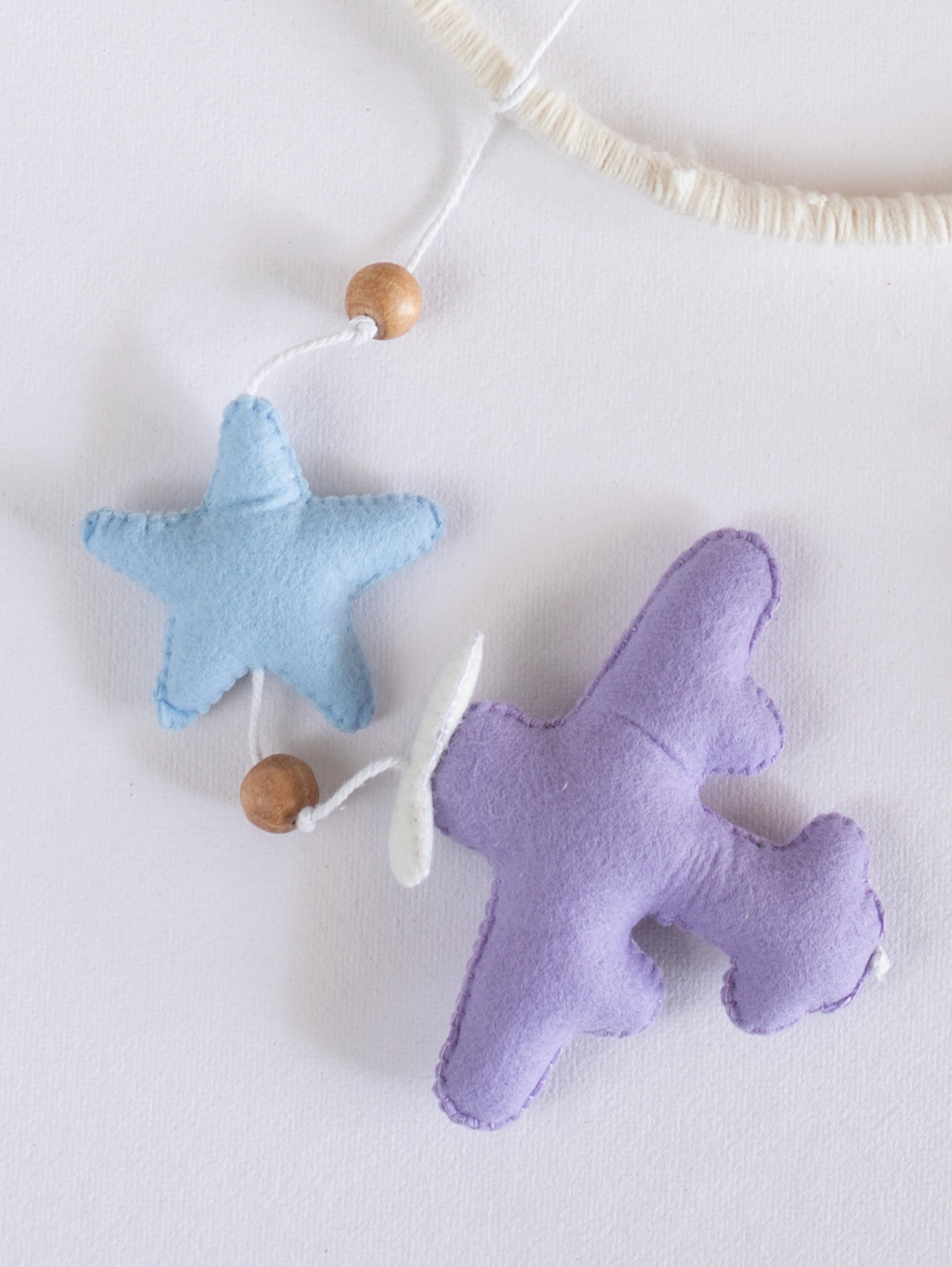 Lavender felt airplane paired with a pastel blue star from the Fly High baby mobile, handcrafted to create a calming sky-inspired nursery.
