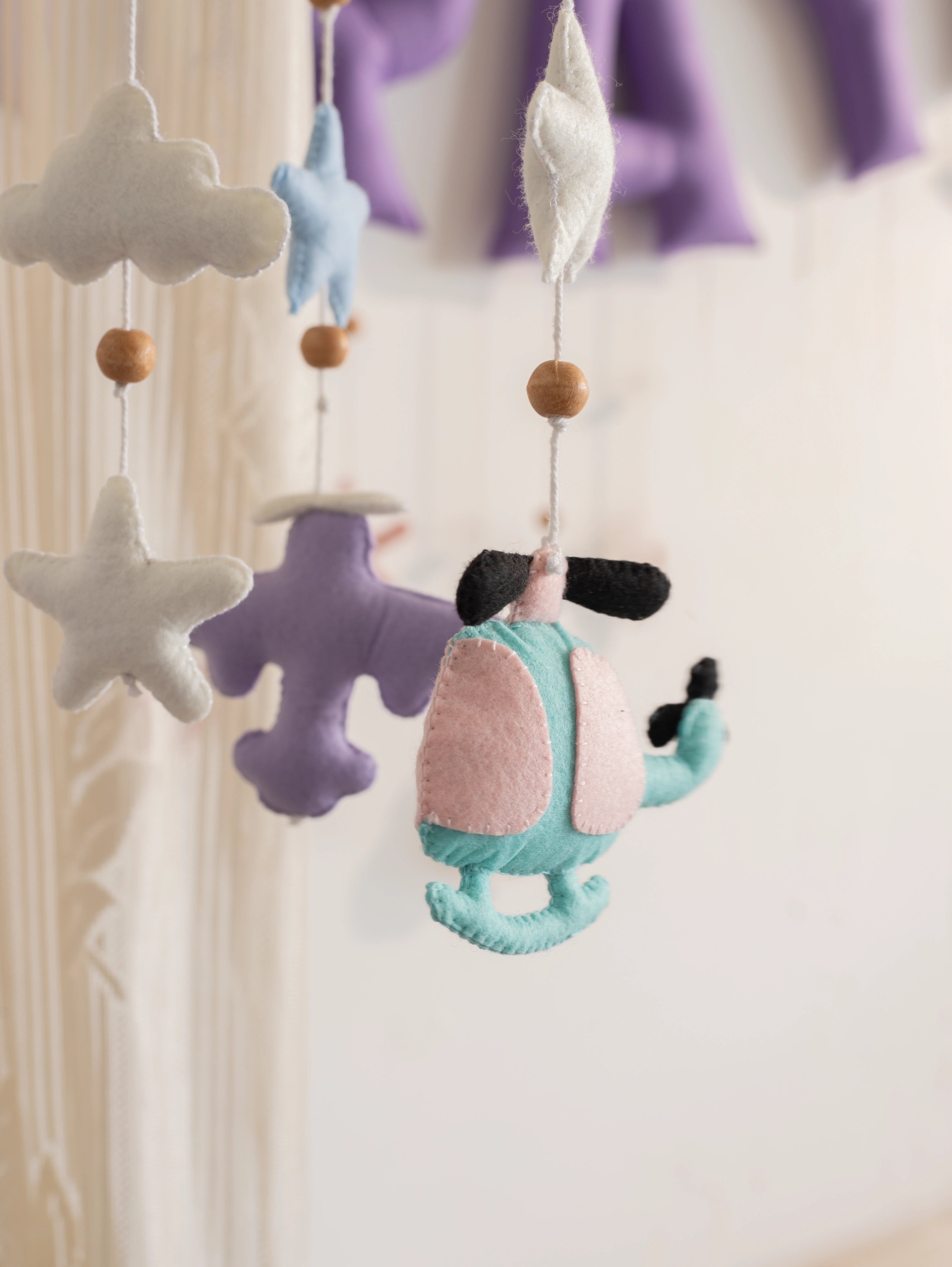 Handcrafted pastel felt helicopter from the Fly High baby mobile with fluffy clouds and stars, designed to inspire adventurous nursery spaces.