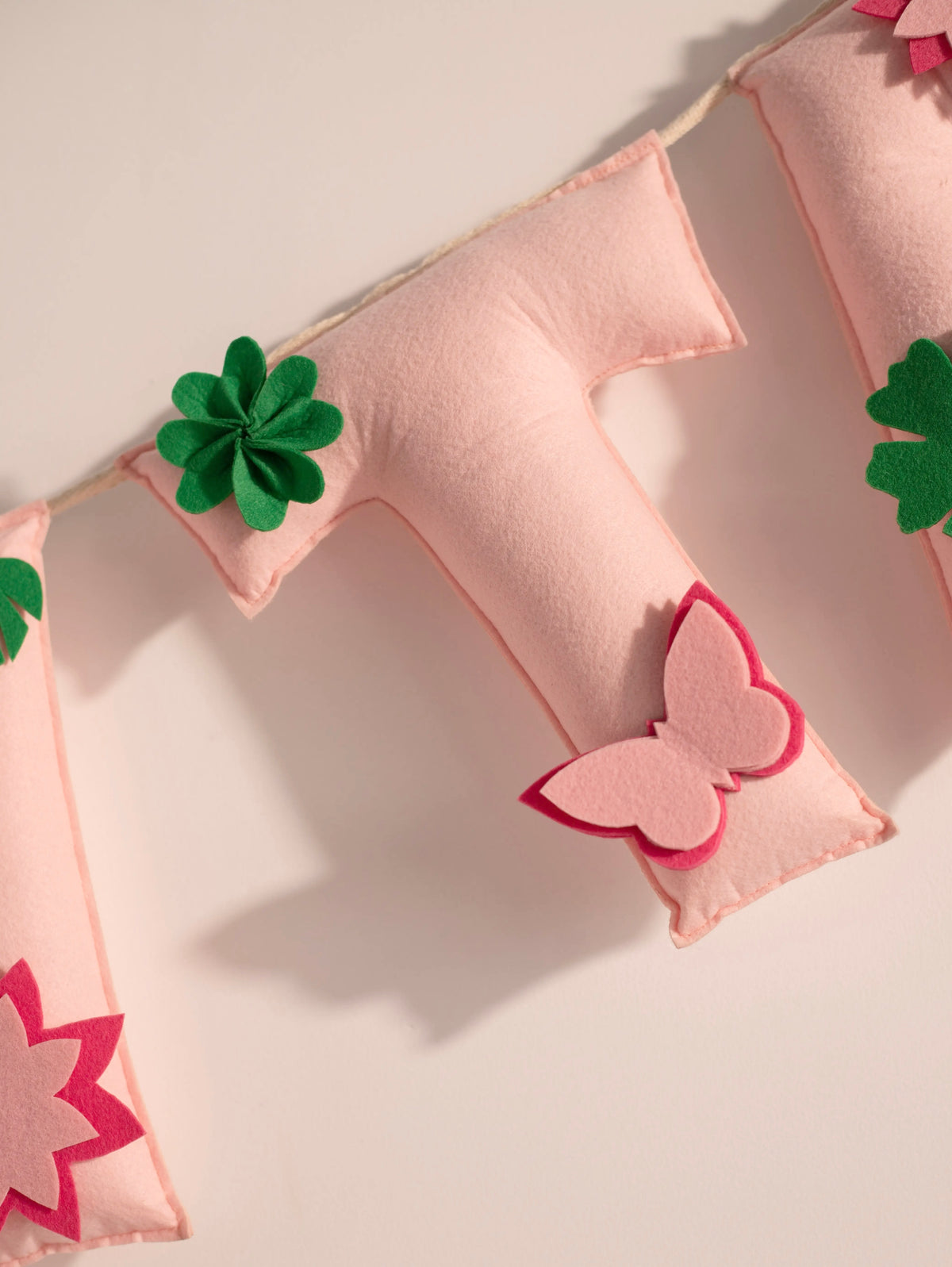 Premium close up of the Garvita felt letter T decorated with handcrafted butterfly and floral banner for nursery wall decoration.
