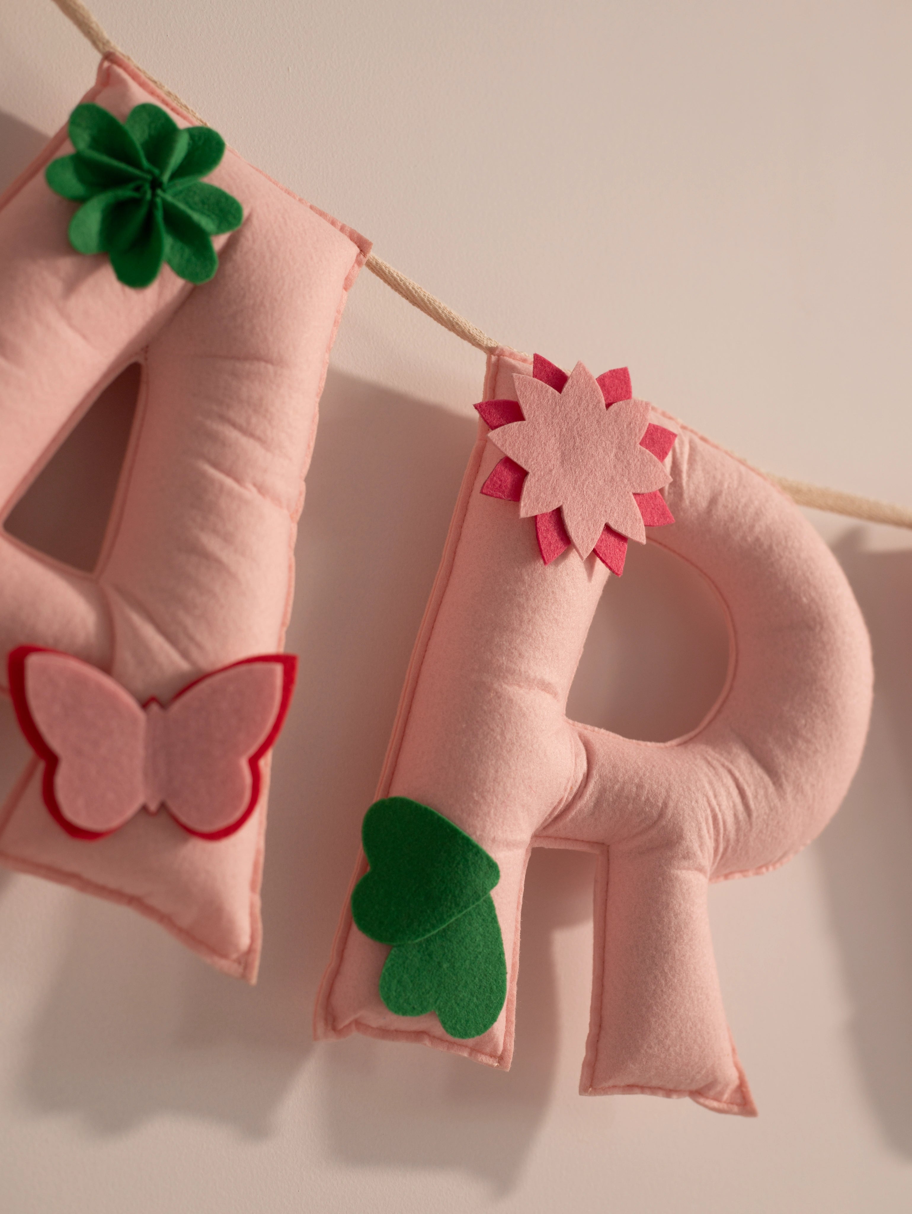 Close-up of the handcrafted felt letter R from the Garvita personalized nursery banner with floral and leaf embellishments.