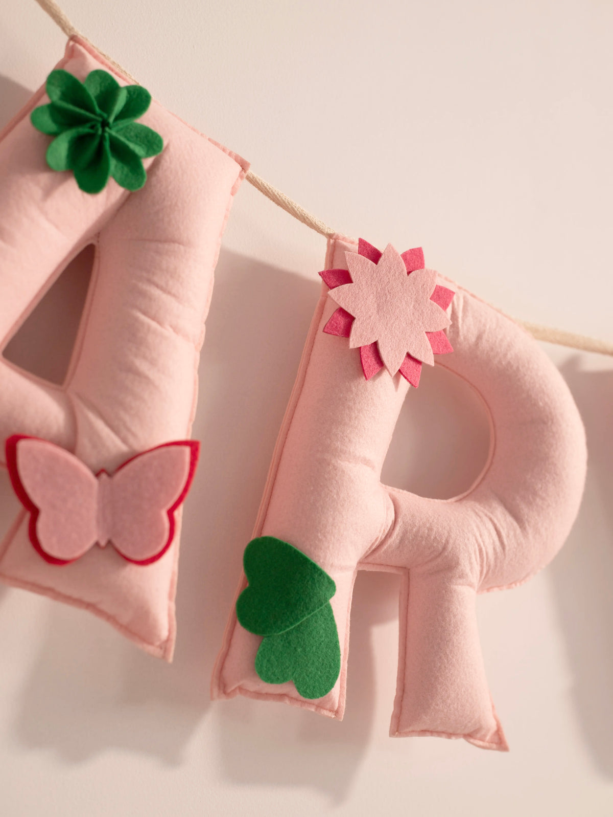 Close up of the handcrafted felt letter R from the Garvita personalized nursery banner with floral and leaf embellishments.