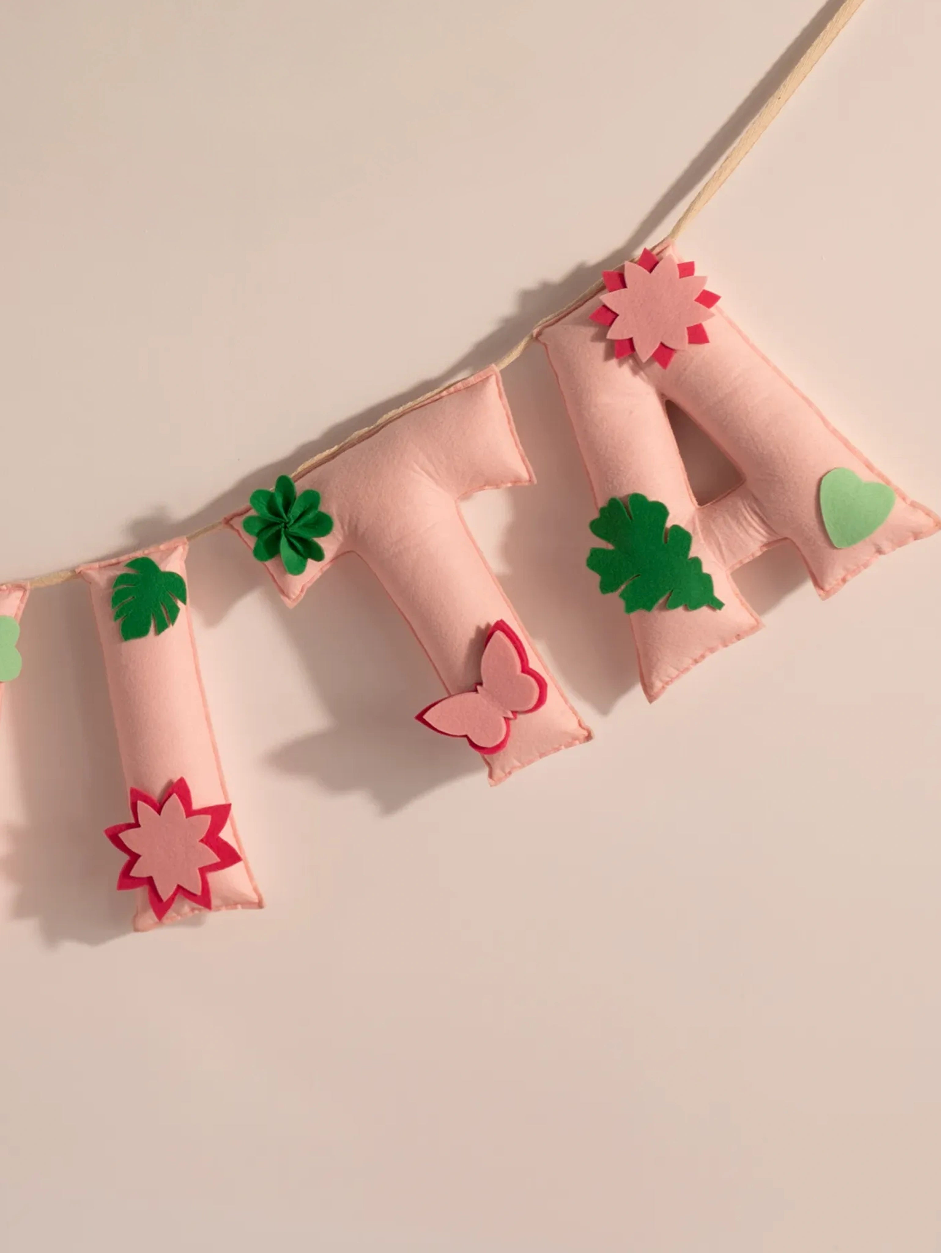 Detailed view of the Garvita handcrafted felt name banner featuring floral appliqués, leafy accents and premium stitched pastel letters.
