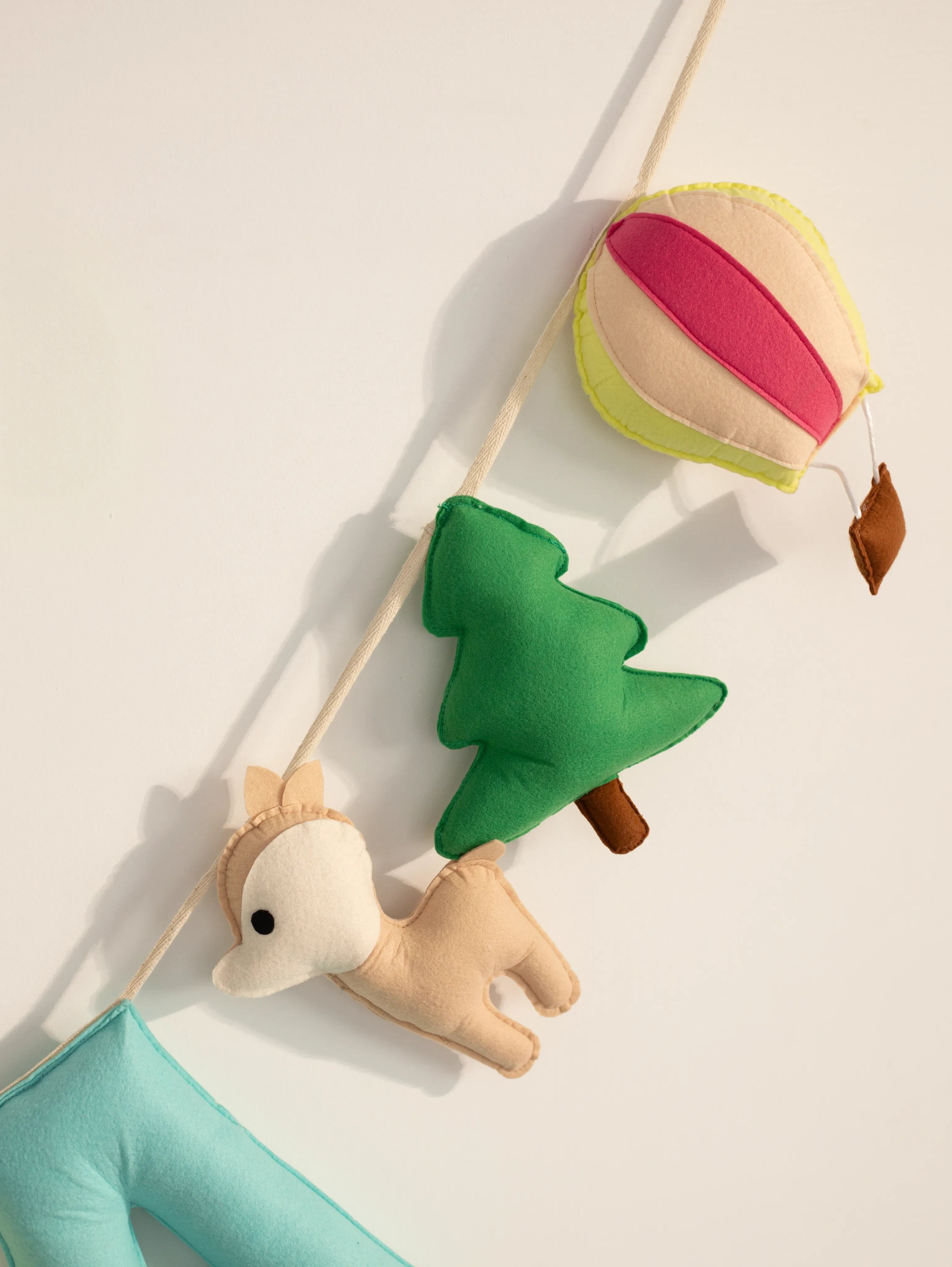 Close-up of the woodland-themed personalized felt name banner showcasing handcrafted felt deer, pine tree, and hot air balloon with premium stitching for baby nursery decor.