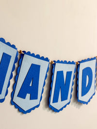 Close-up of handcrafted blue felt alphabet flags on a personalized Nandika nursery name banner