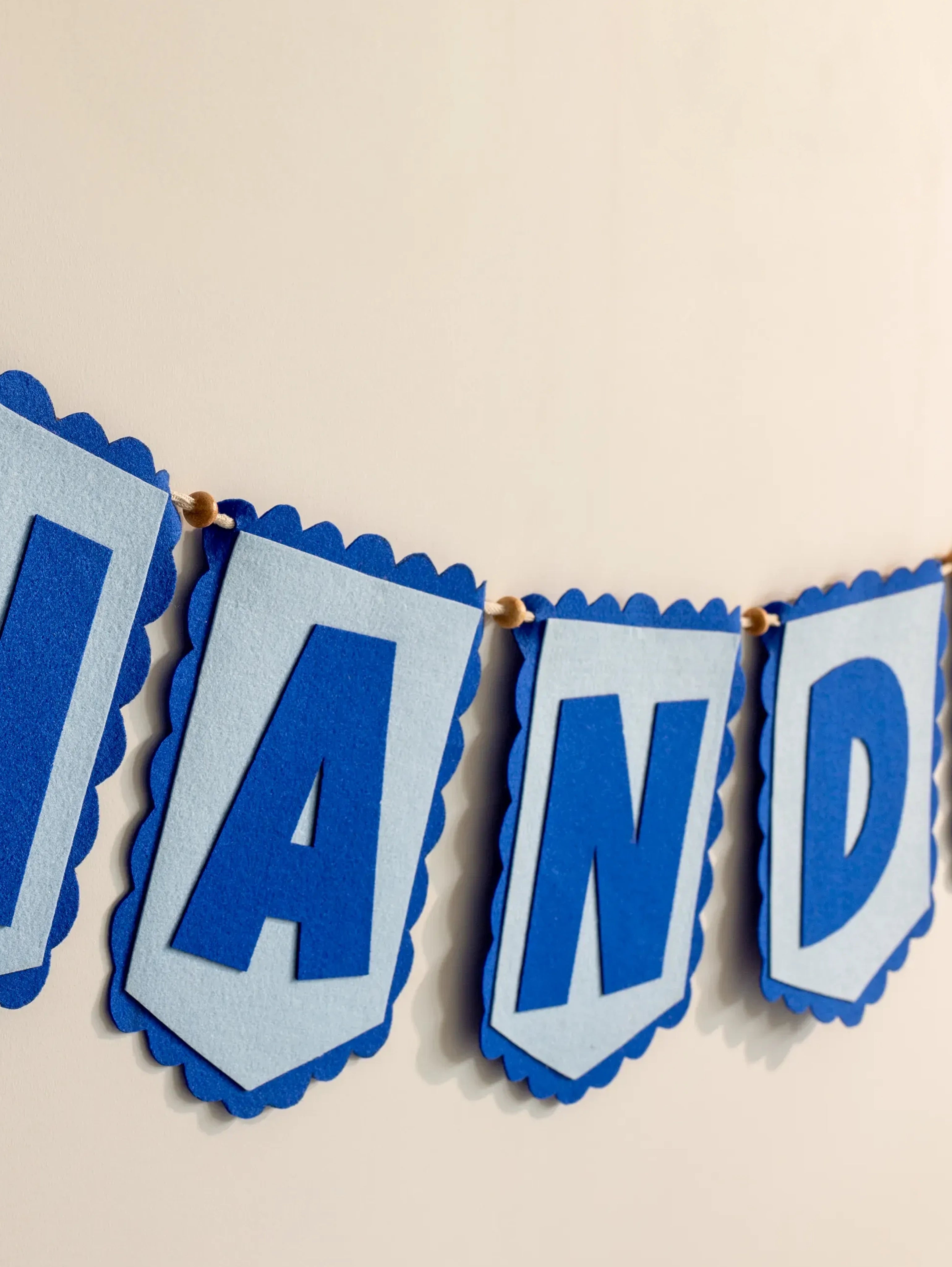 Close-up of handcrafted blue felt alphabet flags on a personalized Nandika nursery name banner