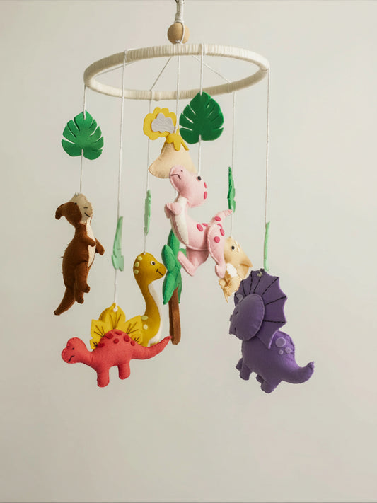 Roar Away premium handcrafted felt dinosaur crib mobile featuring adorable prehistoric characters, tropical leaves, volcano accents, and soft jungle nursery décor.