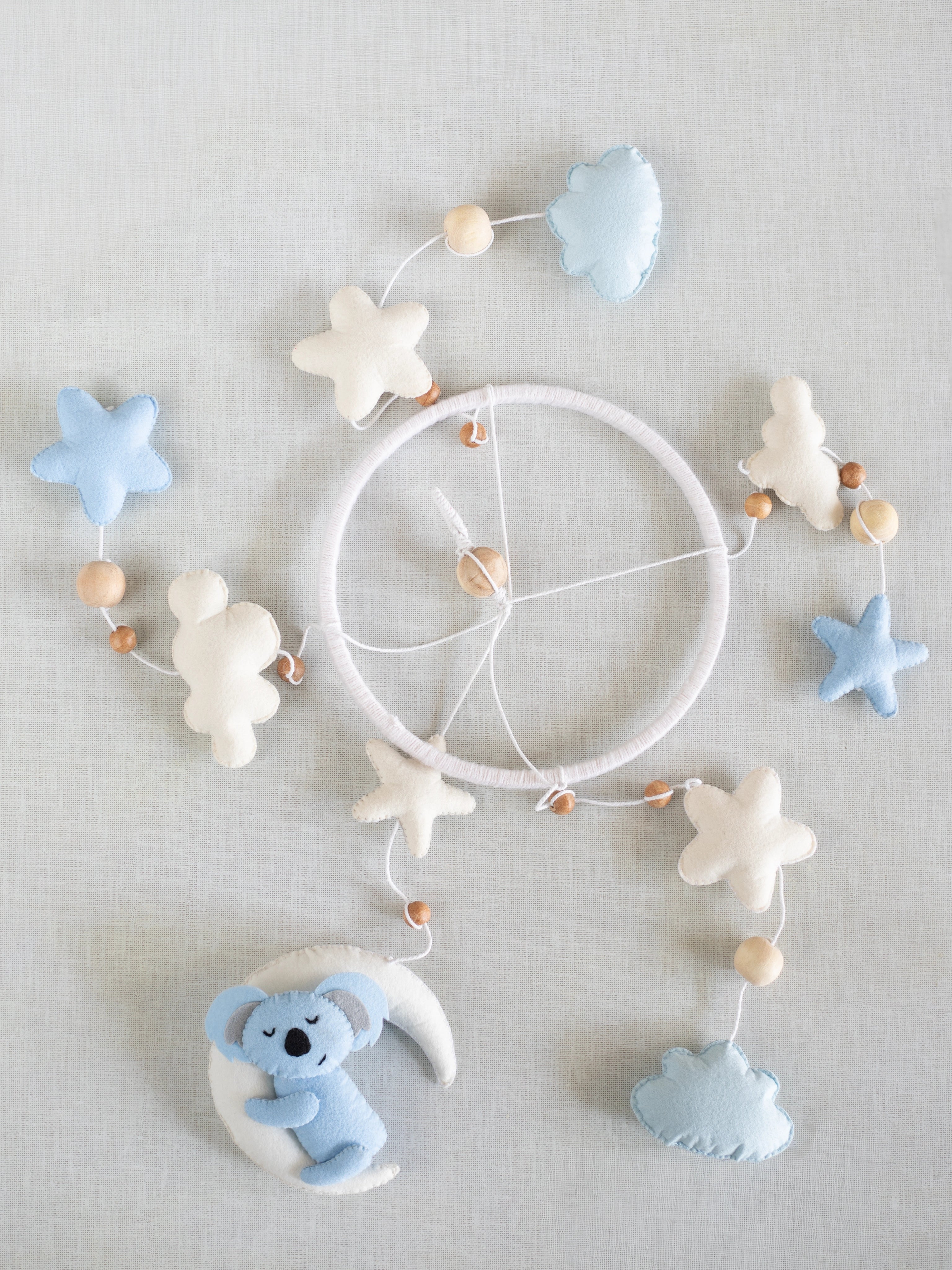 Flat lay of the Sleep Tight handcrafted baby cot mobile featuring a sleeping koala, crescent moon, soft clouds, stars, and wooden bead accents for nursery decoration.