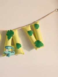 Close-up of the ending letters on the personalized Arav felt name banner featuring green leaf accents and yellow handcrafted flags.