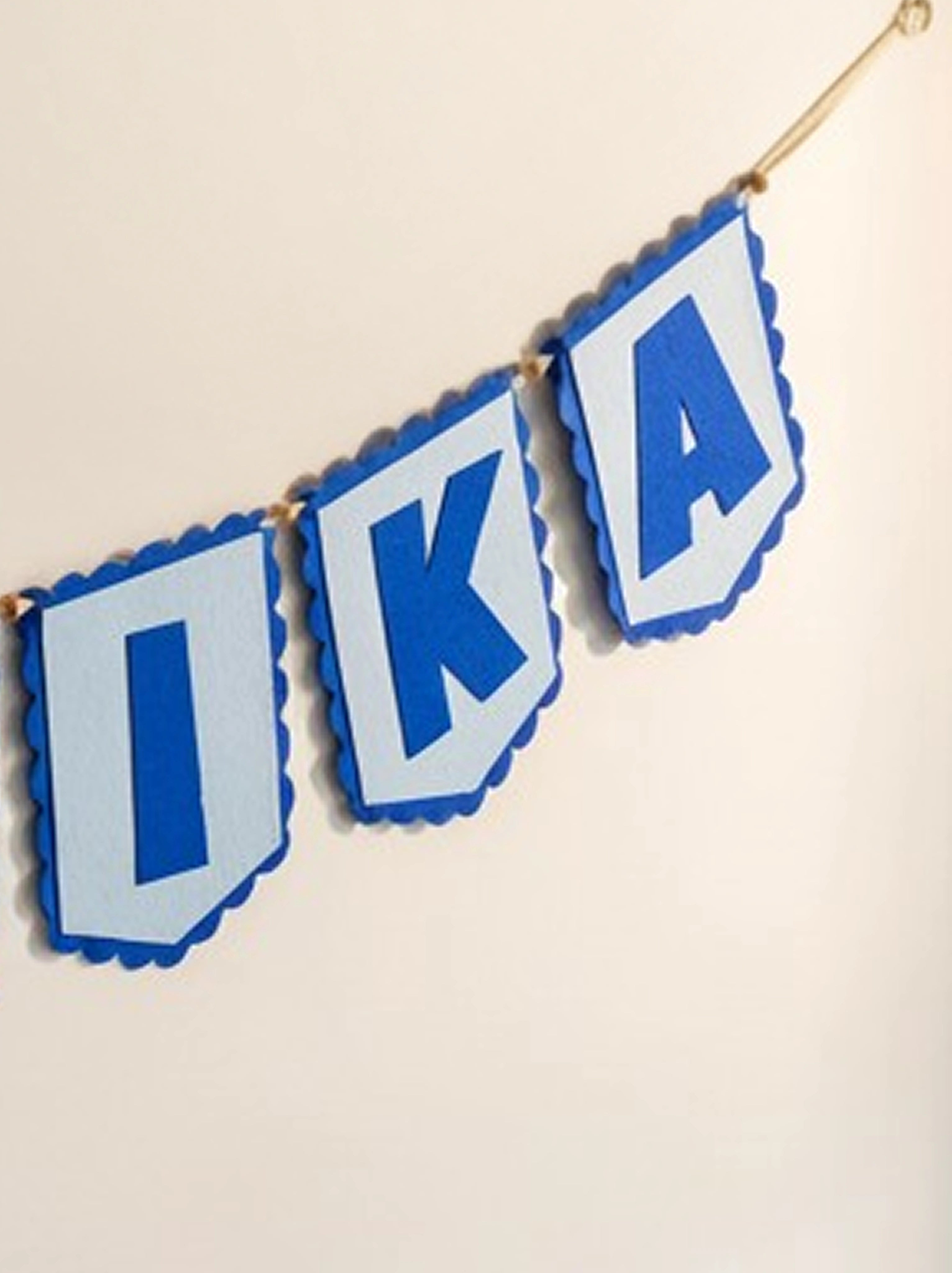 Detailed view of the handcrafted personalized blue felt letter banner showcasing stitched flag pennants suspended from a cotton rope.