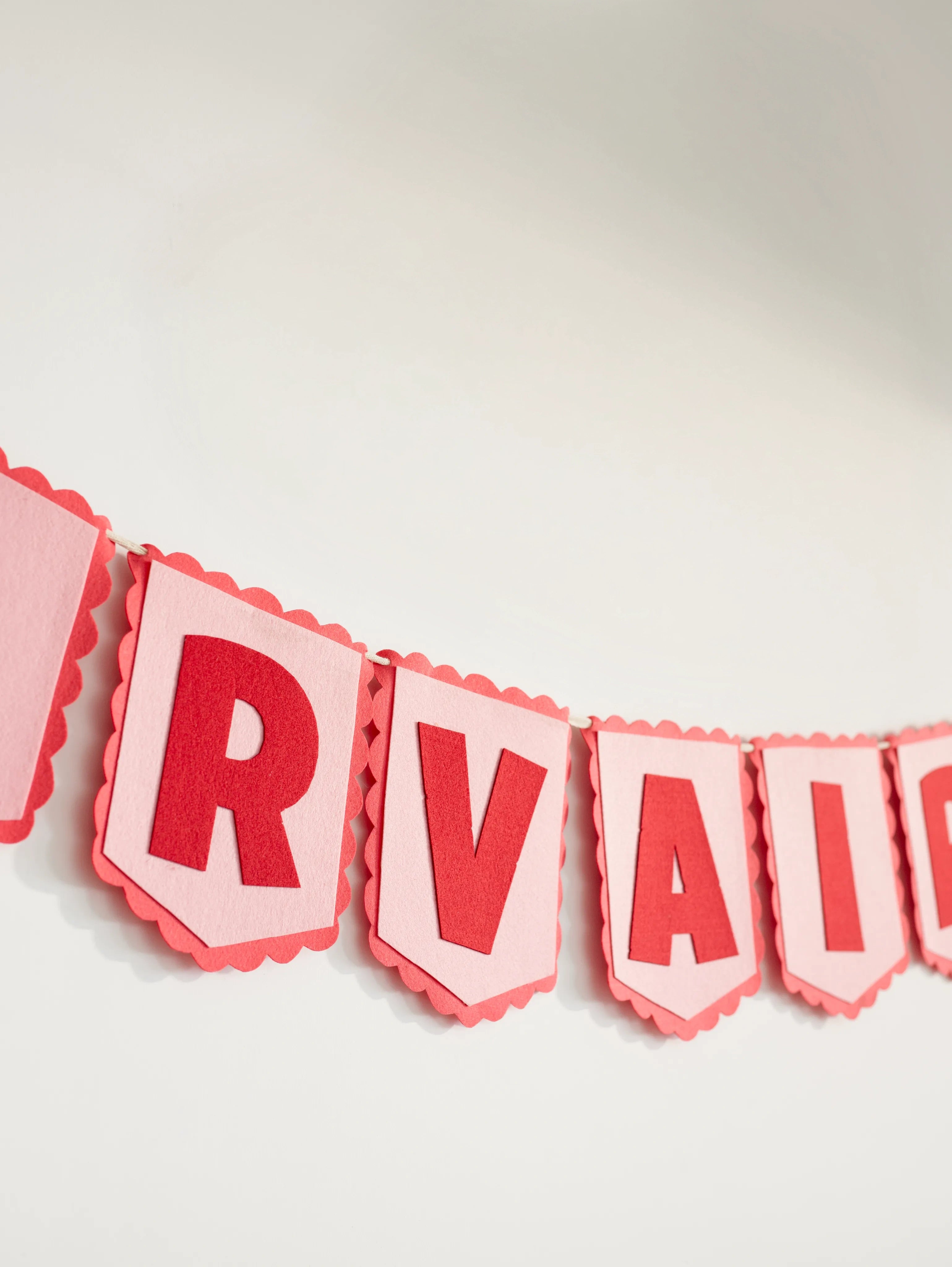 Angled close-up of the personalized Nirvair felt name banner highlighting handcrafted red letters and stitched pennant details