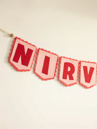 Close-up of the ‘NIRV’ letters on the personalized Nirvair felt name banner with handcrafted red felt lettering.