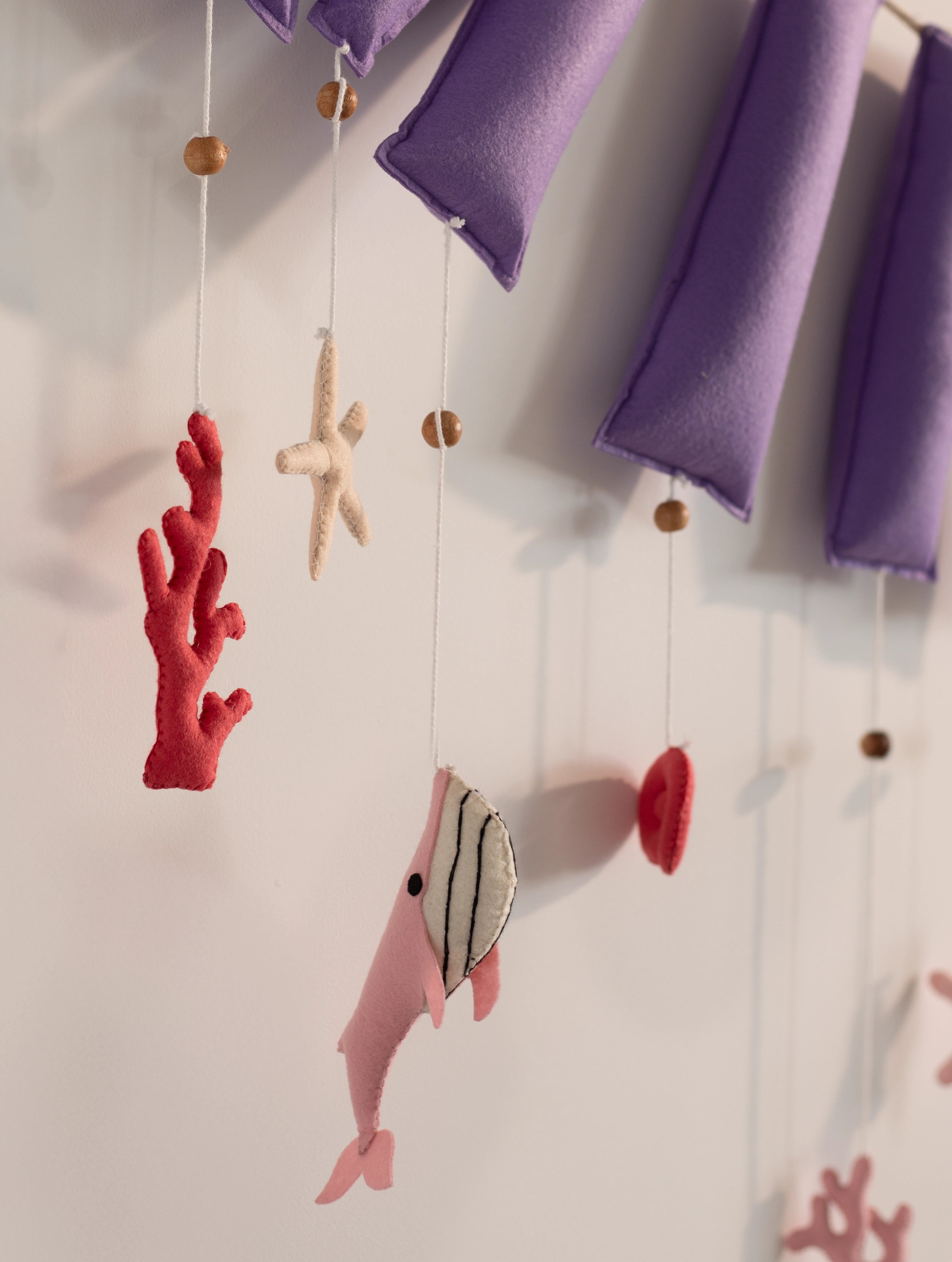 Detailed view of handcrafted coral, seashells, starfish, and purple felt letters on an ocean-themed personalized nursery name banner