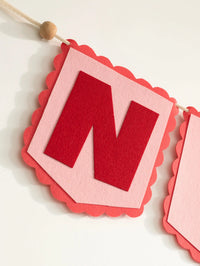 Macro close-up of the handcrafted red felt letter ‘N’ from the personalized Nirvair nursery name banner.