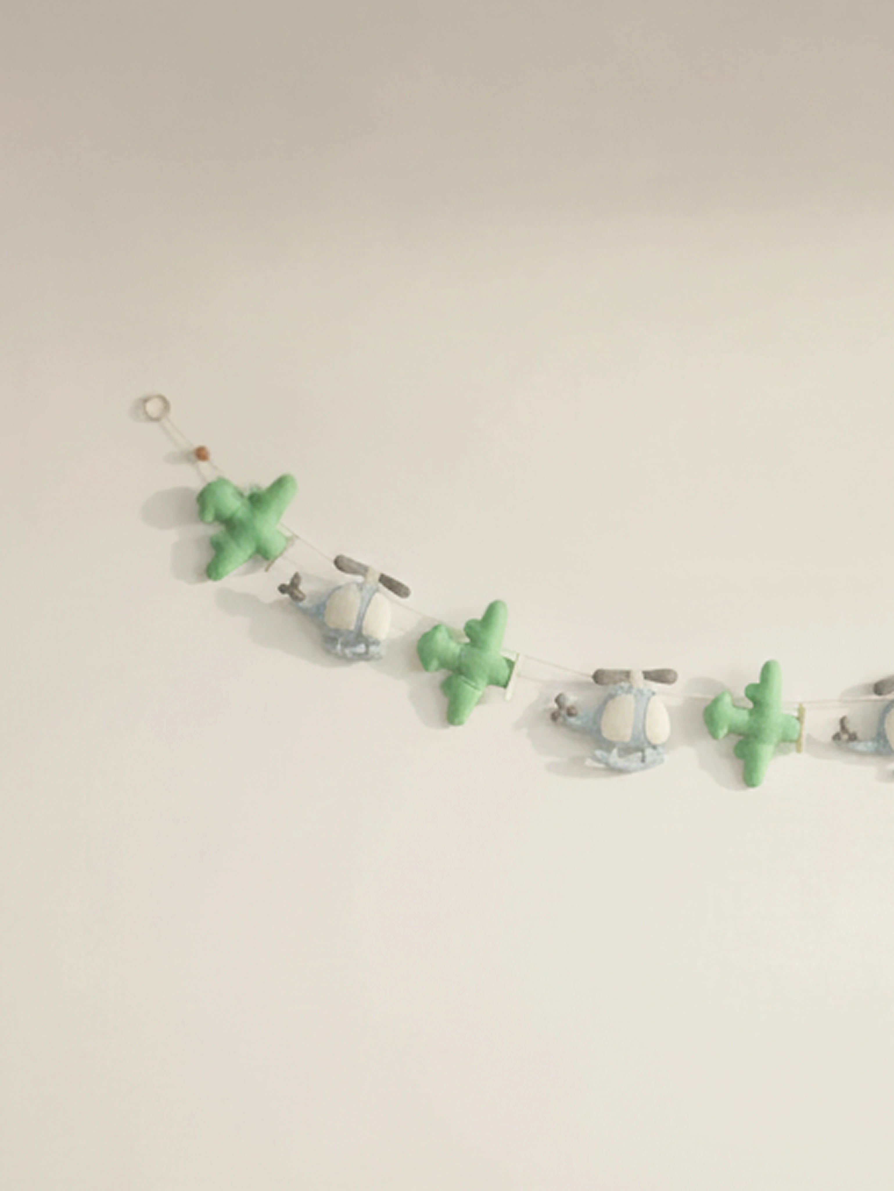 Close-up of the left section of the To The Moon felt banner showcasing handcrafted airplanes and helicopters in soft pastel tones.