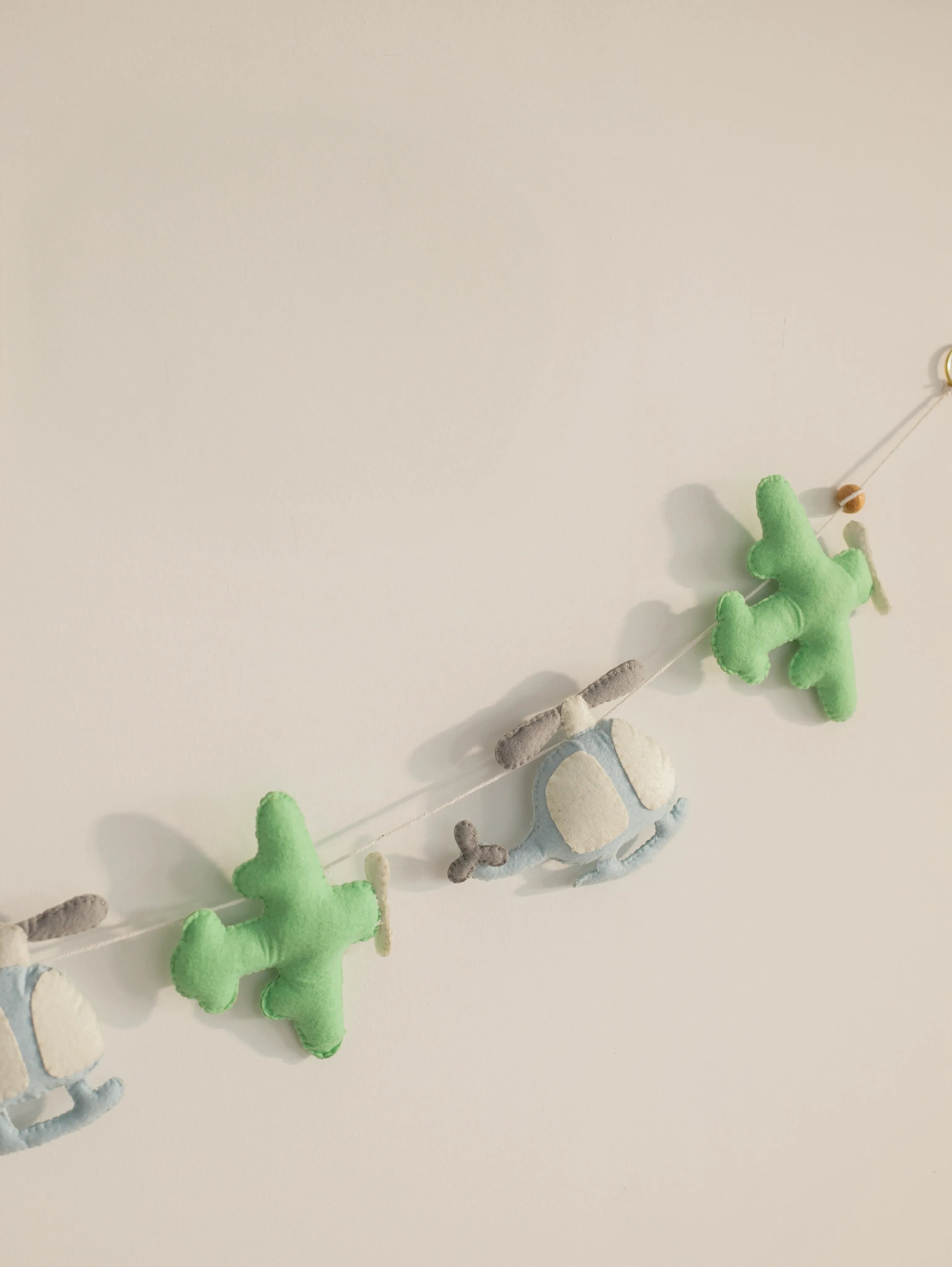 Close-up of the To The Moon felt wall hanging featuring alternating plush airplanes and helicopters for a modern nursery theme.