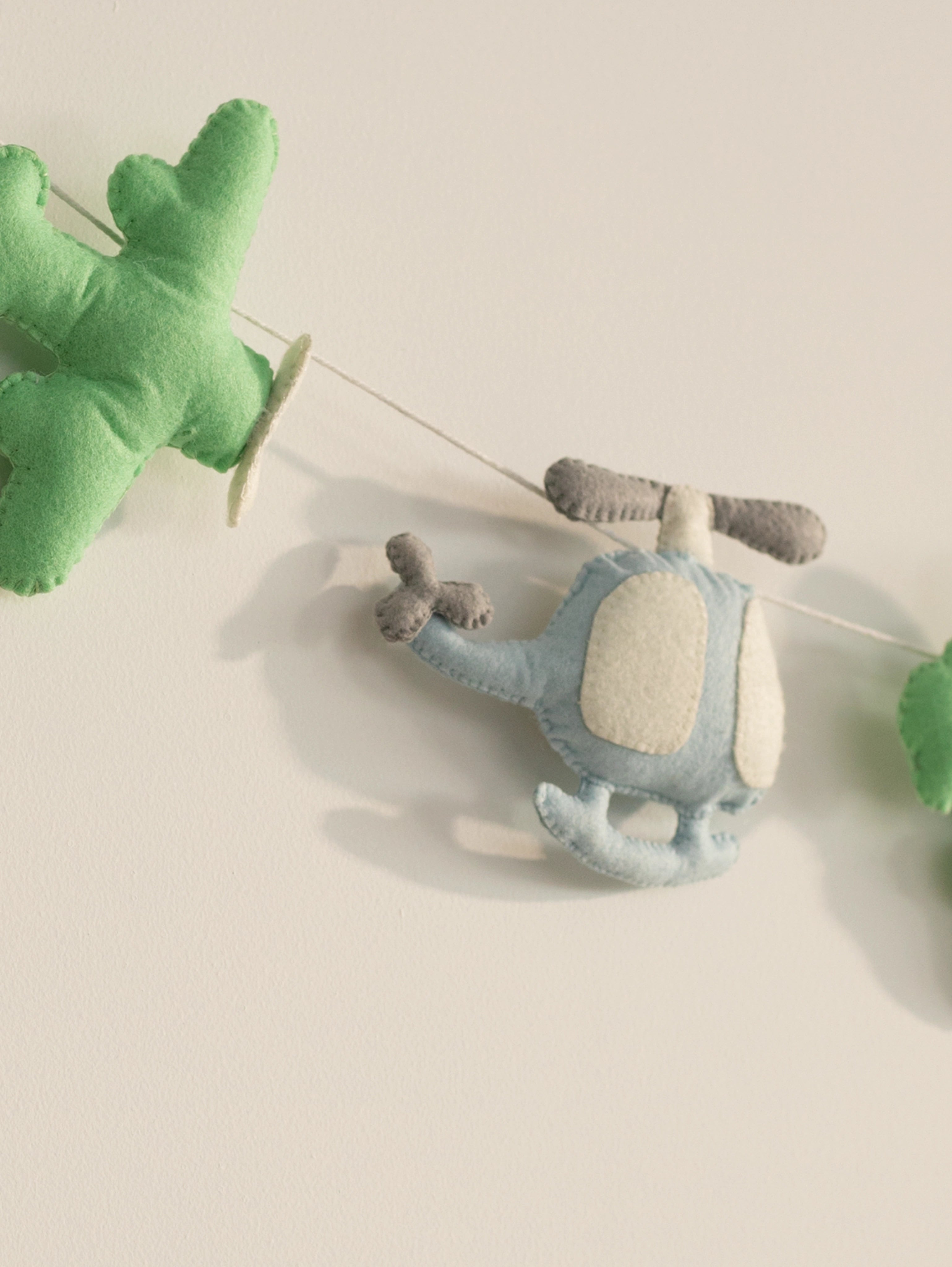Detailed close-up of a handcrafted blue felt helicopter from the To The Moon nursery banner designed for aviation-themed baby room decor.