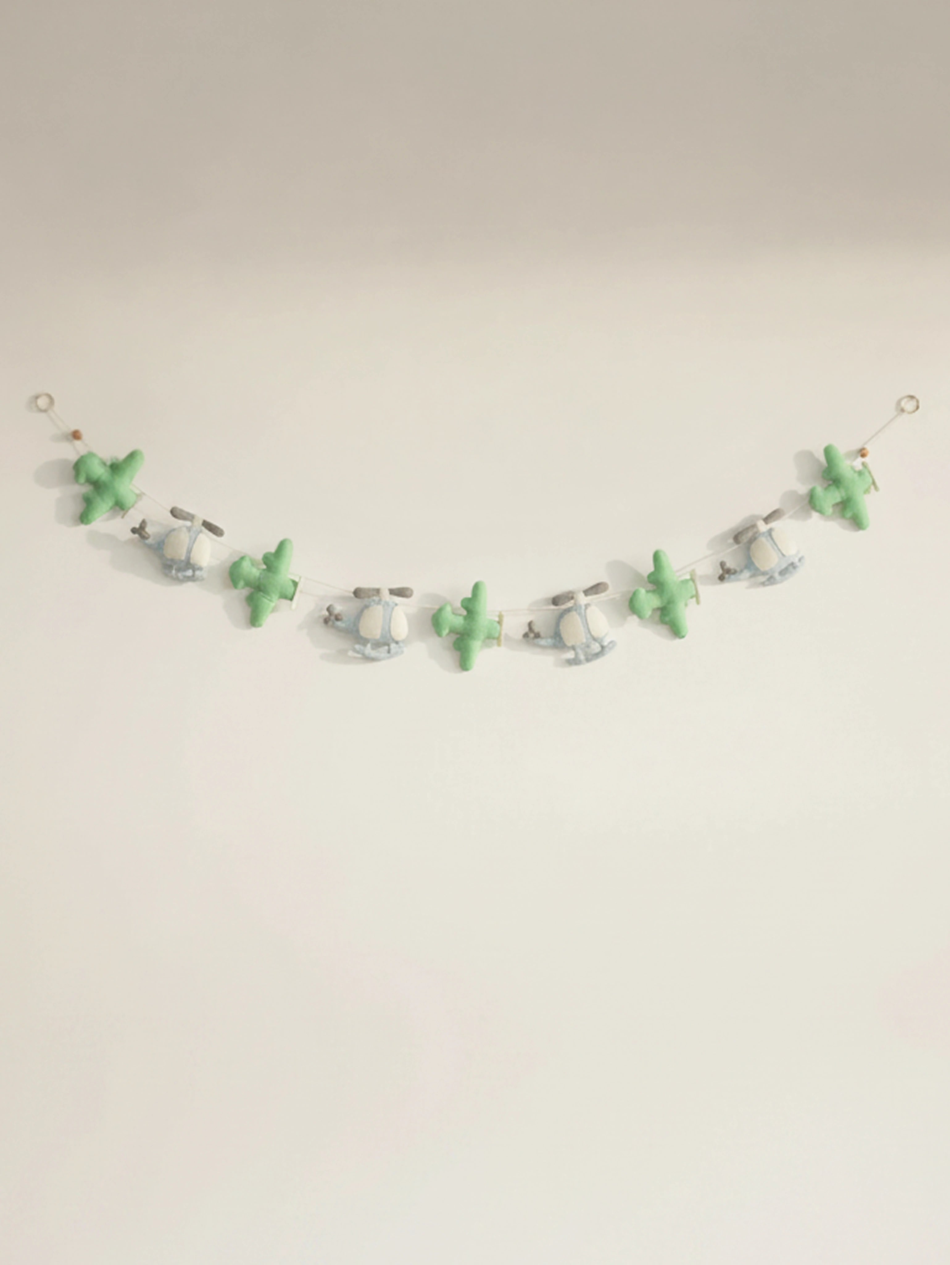 Handcrafted To The Moon felt nursery banner featuring pastel green airplanes and blue helicopters for baby room wall decoration.