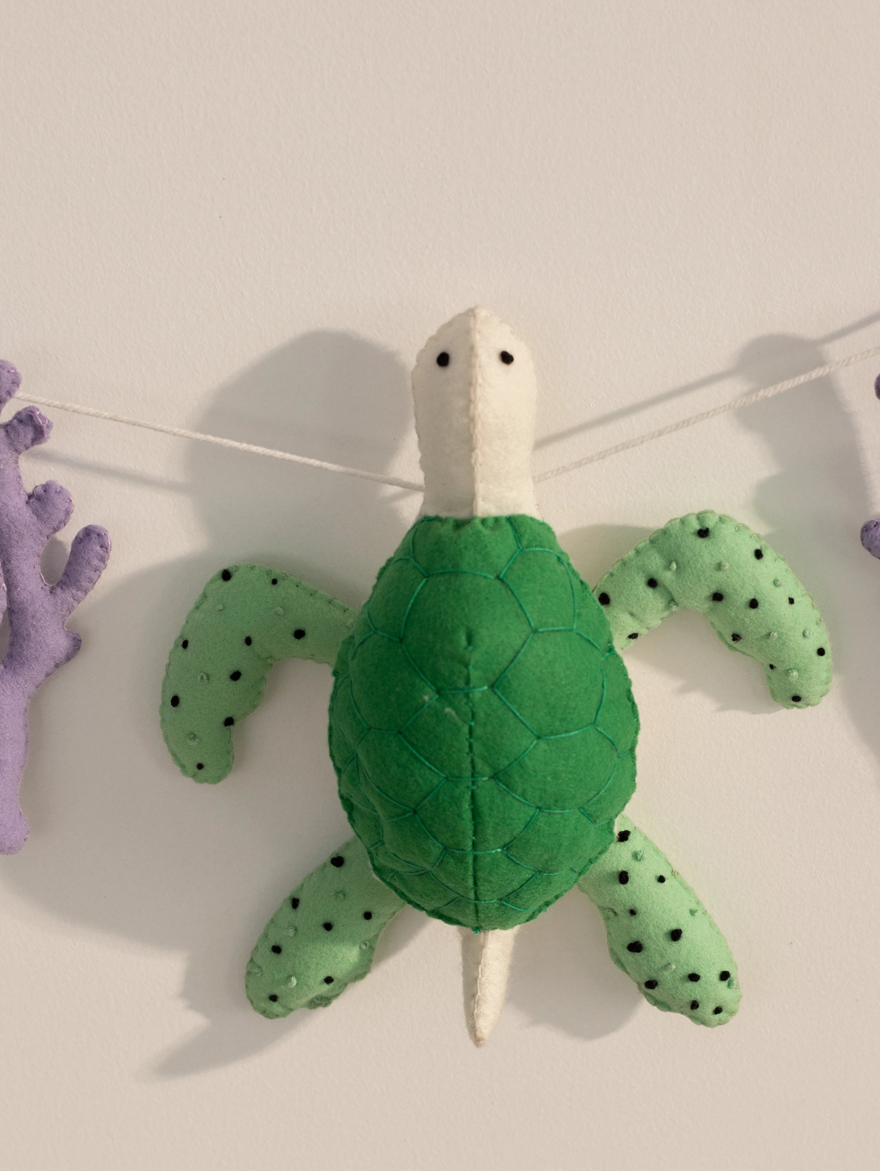 Detailed view of a handcrafted green felt sea turtle with textured shell from the Under the Sea nursery wall hanging.