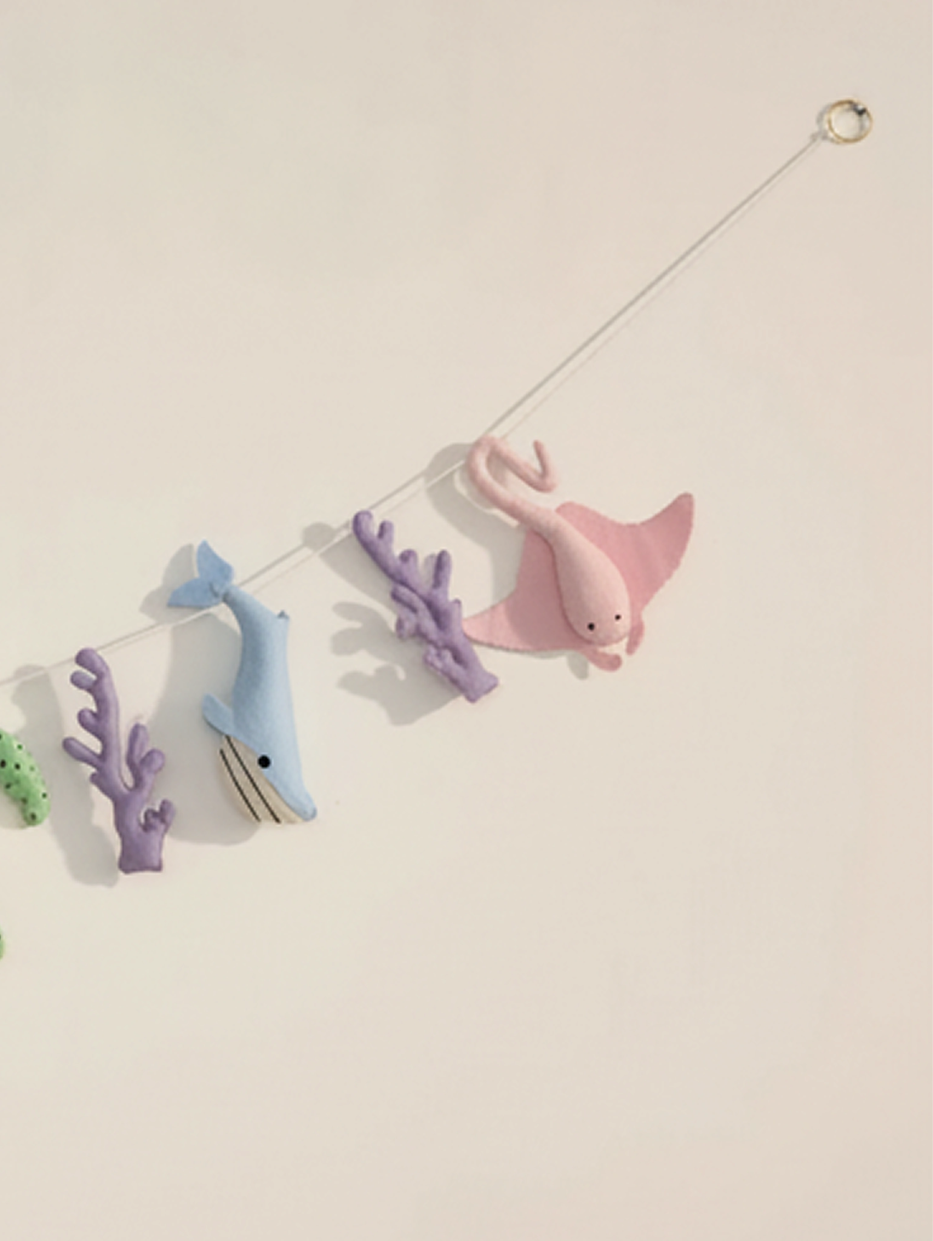 Right-side close-up of the Under the Sea felt wall banner highlighting a pink stingray, whale and coral decorations for a modern nursery.