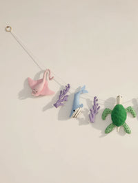 Left-side detail of the Under the Sea felt nursery garland showcasing a pink stingray, blue whale and handcrafted coral elements.