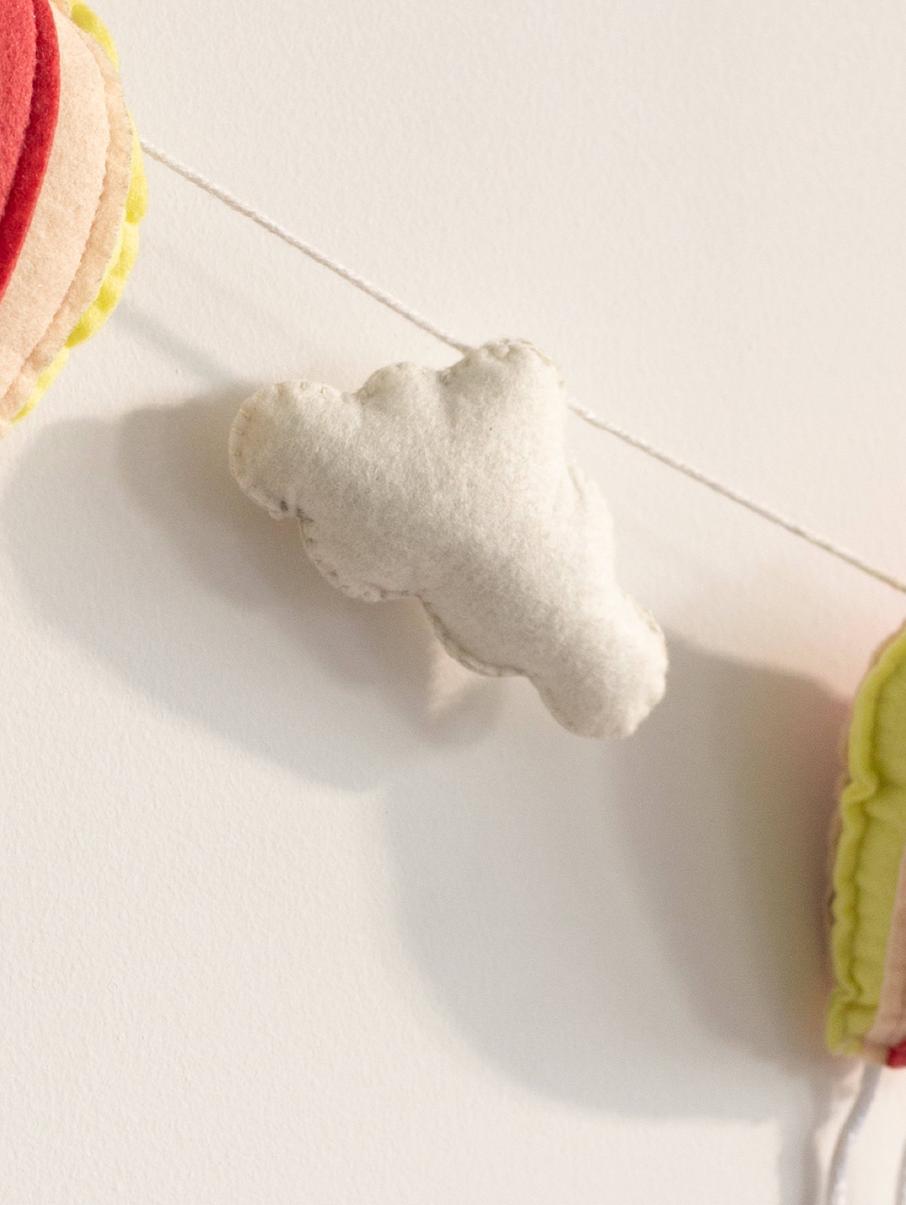 Close-up of a plush white felt cloud from the Up and Away nursery banner designed for dreamy baby room wall decoration.
